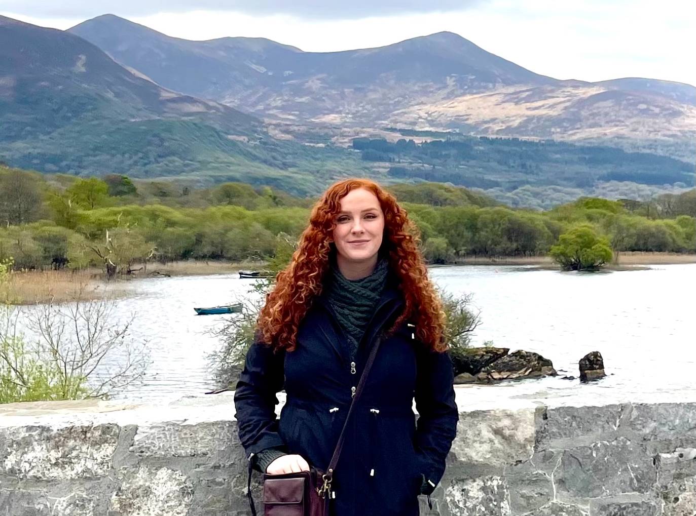 An alum stands with hills in the distance on trip to Ireland